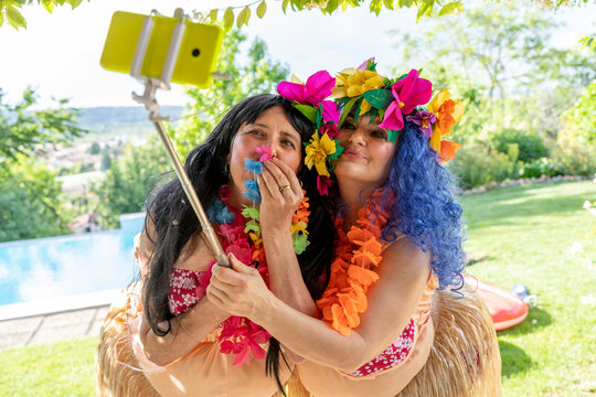 two smiling female friends dressed in Hawaiian costumes take a selfie
