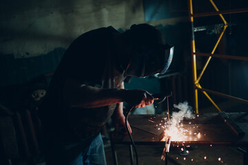 Welder welding metal construction on workshop