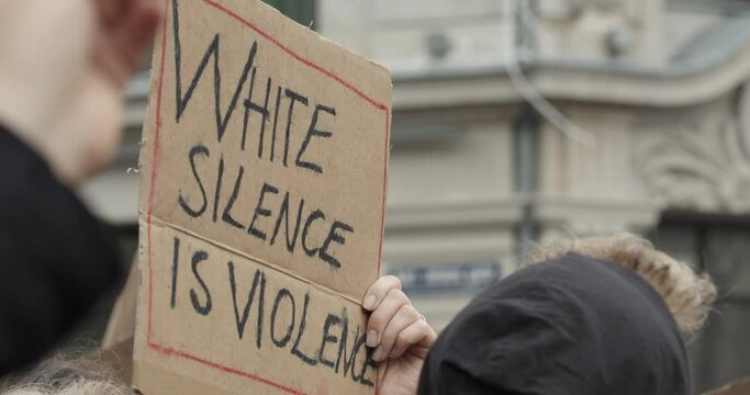 Handheld slow motion shot of placard with "WHITE SILENCE IS VIOLENCE" in killing protest rally, in Oslo Norway