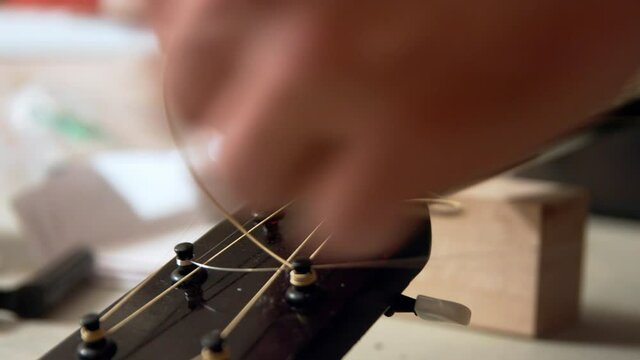 Twisting the guitar strings around to a circle of the extra length of the string around a knob.