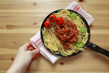 pasta with Basil tomato sauce and minced meat, serving spaghetti in a pan on a wooden background