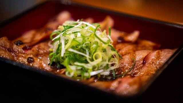 Japanese cooked wagyu beef slices garnished with green onion in a bento box