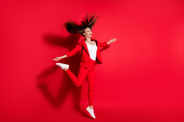 Full length profile photo of attractive worker lady having fun jumping high up good mood rejoicing vacation time wear blazer suit pants footwear isolated bright vivid red color background