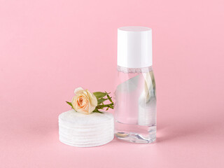 Skin tonic lotion or micellar water, cotton pads and small rose flower on a pastel pink background. Cosmetics for moisturizing and cleansing. Skin, hair or body care.