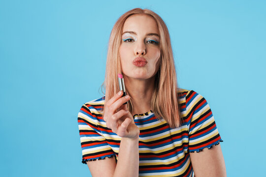 Image of attractive caucasian girl making kiss lips and holding lipstick