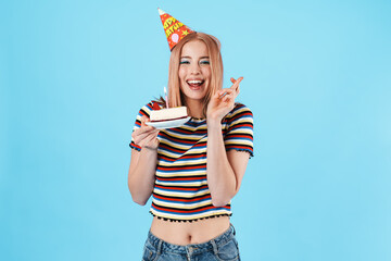 Image of cheerful girl holding cake and fingers crossed for good luck