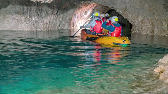 Rear view of visitors kayaking in underground waters of mount Peca, Slovenia