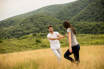 Happy young couple in love walking through grass field