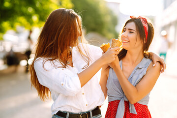 Two young female friends having fun and eating ice cream. Young women enjoy summer and vacation. 