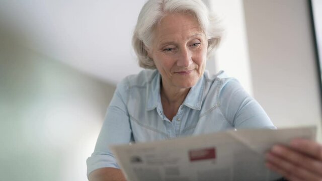 Portrait of senior woman reading newspaper