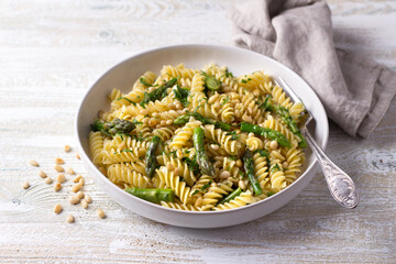 Vegan pasta with asparagus, garlic, pine nuts and parsley on a wooden background, top view. simple...