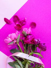 Bouquet of fresh pink peonies on pink background with satin ribbon . Flowers delivery.
