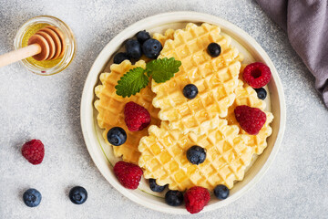 Corrugated waffle cookies with fresh raspberries and blueberries on a concrete background. Copy space.