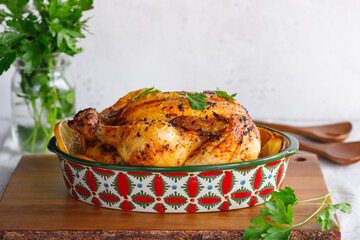 Whole roasted chicken with fresh parsley and lemon wedges in a festive dish