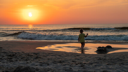 Fototapeta na wymiar dziecko na plaży o zachodzie słońca