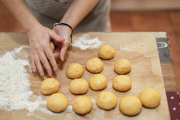 Feminine hands making small balls with raw short pastry.