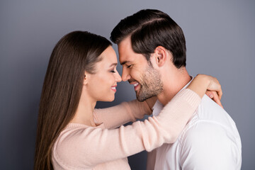 Close-up profile side view portrait of his he her she nice attractive lovely cute cheerful tender gentle sweet couple embracing cuddling isolated over gray violet pastel color background