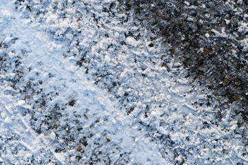 Track from car tire on asphalt covered with snow