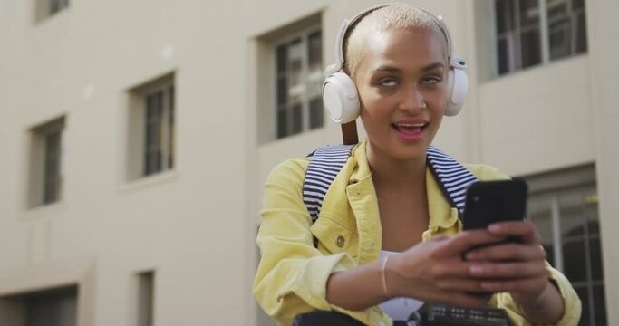 Mixed race woman listening music on the street on her e scooter