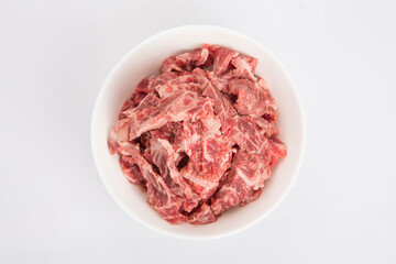 isolated close up flat lay top view shot of sliced raw beef fillet pieces in a white bowl on a white background