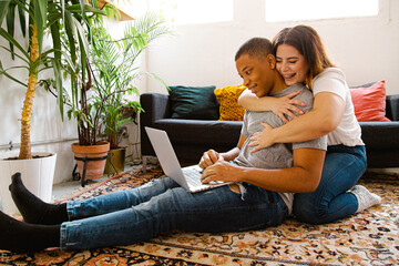 Interracial couple sitting on the carpet in the living room at home
