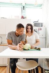 Obraz na płótnie Canvas Interracial couple cooking at the kitchen