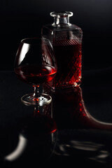 Glass of brandy and a carafe on a dark background.