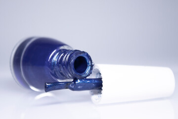A bottle with spilled blue nail polish on white background. nail lacquer. Nail manicure concept. Isolated, copy space. 