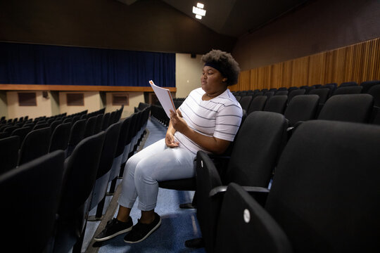 Side view of student reading a text in a theater