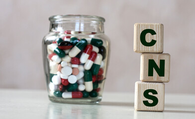 CNS (Central Nervous System) - acronym on cubes on a light background with a capacity with tablets