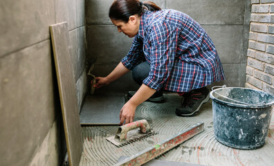 Female manual worker laying a new tile floor on a terrace