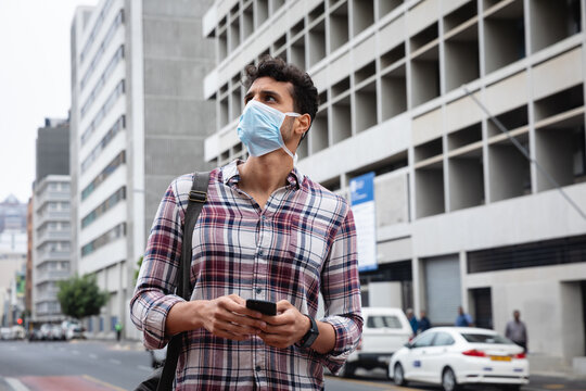 Caucasian man wearing a covid19 coronavirus mask outside and using his phone