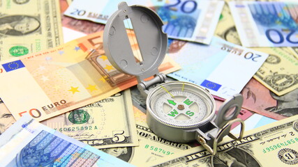 Small compass on international paper money. Where to move? Direction in economy to be found.