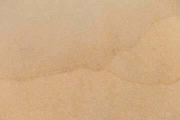 Fototapeta na wymiar Fine sand background, wave pattern on brown sand beach