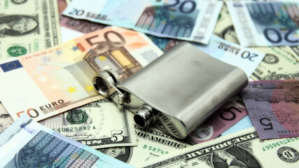 Money and flask for drink. Alcohol abuse concept.