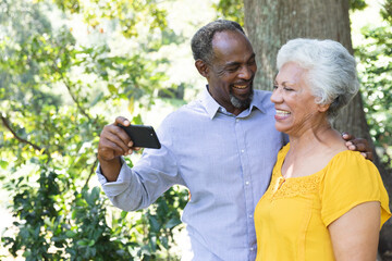 Smiling senior couple taking selfie in garden