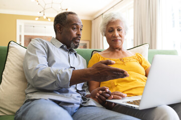 Senior African American couple using laptop in a canape