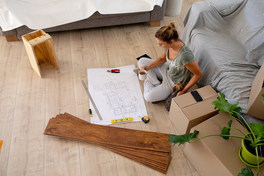 Women in Social Distancing sitting on the floor examining a plan