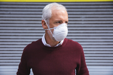 Middle aged man wearing coronavirus Covid 19 mask on the go 