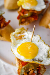 Basque pintxo made with onion, red & green pepper topper with a small fried egg.