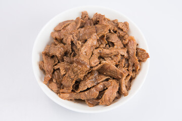 isolated close up flat lay top view shot of sliced beef fillet pieces in a white bowl on a white background