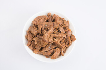 isolated close up flat lay top view shot of sliced beef fillet pieces in a white bowl on a white background