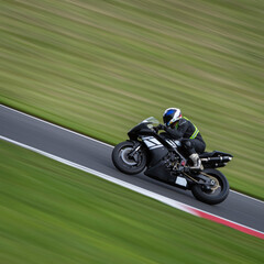 A panning shot of a black racing bike cornering on a track