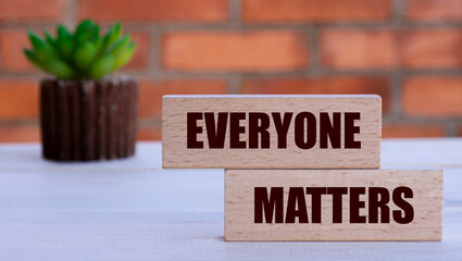 EVERYONE MATTERS - the words on cubes against the background of a brick wall with a cactus.