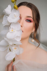 Obraz na płótnie Canvas Amazing model girl bride with bright makeup looks at the camera. Portrait. Bride portrait with bright makeup and orchid