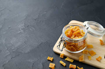 Dried pumpkin slices in jar on a dark stone background. Candied pumpkin. Copy space