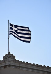 Greek flag waving on the top of a building in Athens, Greece.