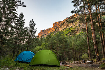 Two tents with fire place and a mountain top on sunset