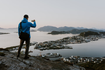 Traveller is taking pictures of scenic norwegian city view from the mountain. Travel and hiking concept