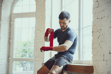 Preparing. Young caucasian man training at home during quarantine of coronavirus outbreak, doing...
